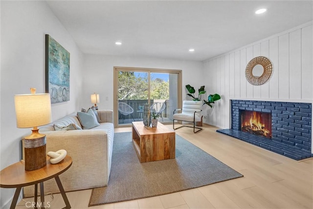 living area with a brick fireplace, recessed lighting, and wood finished floors