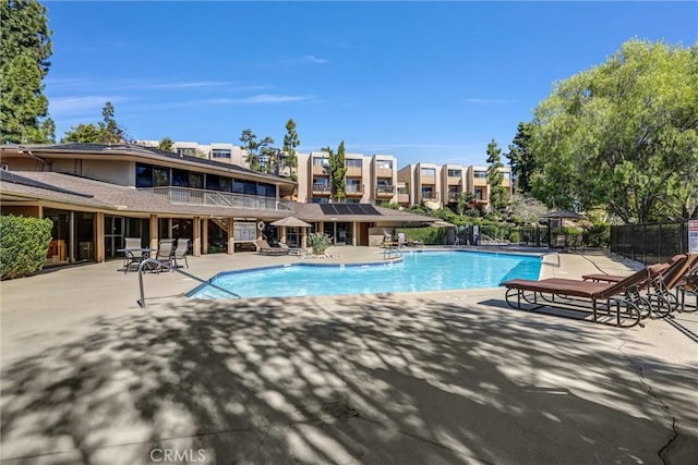 community pool with a patio area and fence