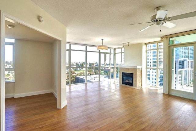 unfurnished living room with a healthy amount of sunlight, floor to ceiling windows, baseboards, and wood finished floors