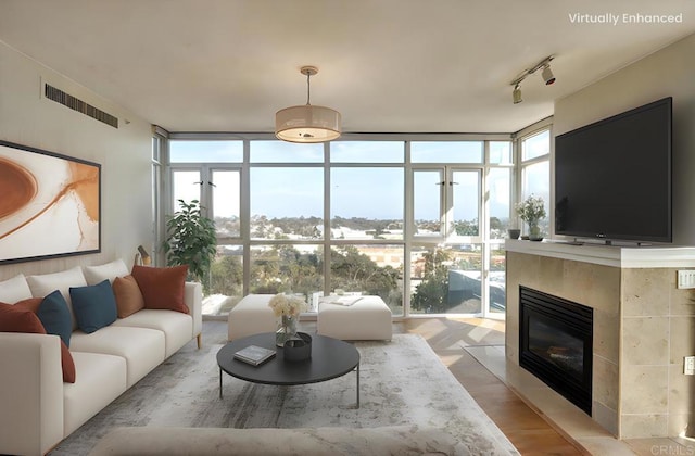 living area with visible vents, light wood-style flooring, a fireplace with flush hearth, expansive windows, and track lighting