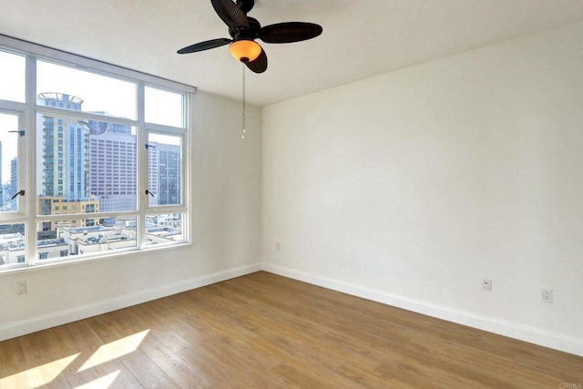 unfurnished room with a healthy amount of sunlight, baseboards, and wood finished floors