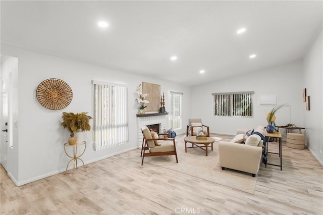 sitting room with vaulted ceiling, a brick fireplace, light wood-style flooring, and recessed lighting