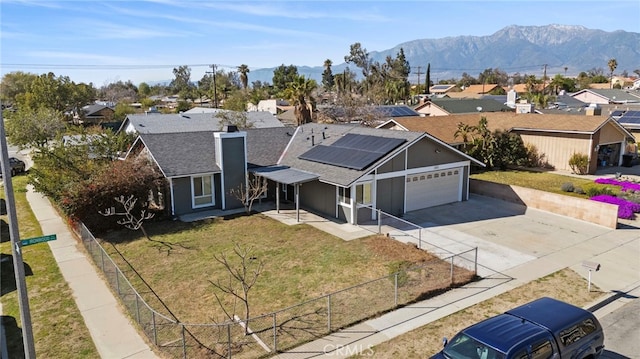 view of front of property featuring a front lawn, fence private yard, a residential view, and roof mounted solar panels