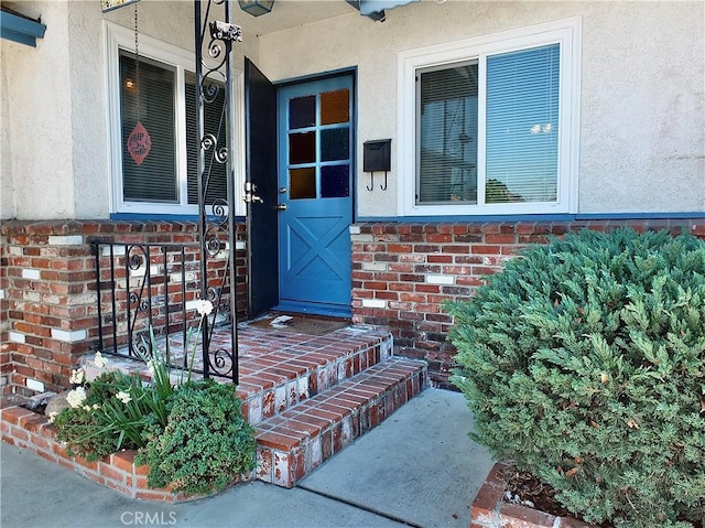 doorway to property with stucco siding and brick siding