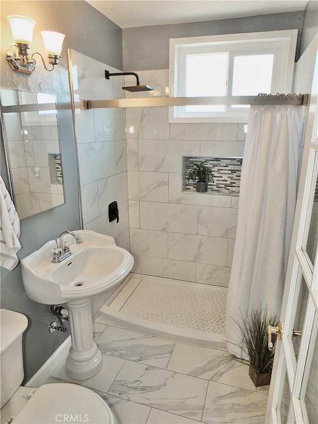 full bath featuring marble finish floor, a tile shower, and toilet