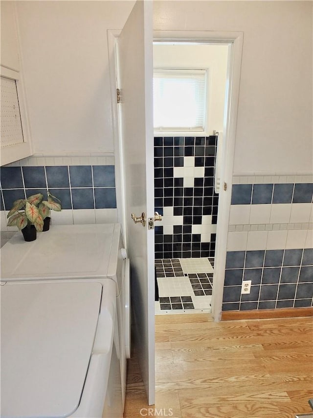 interior space with wainscoting, tile walls, and washing machine and clothes dryer