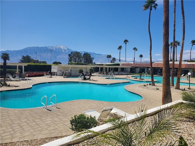 community pool with a mountain view and a patio
