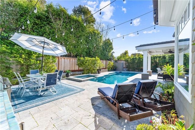 view of swimming pool with outdoor dining area, a pool with connected hot tub, a patio area, and a fenced backyard