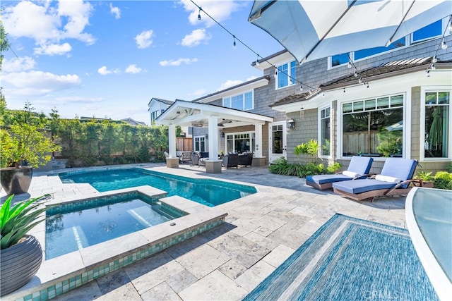 view of pool featuring a pool with connected hot tub, a patio, fence, and an outdoor hangout area