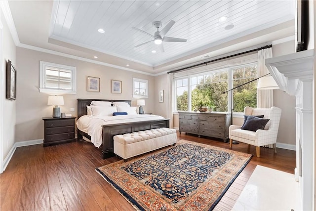 bedroom with hardwood / wood-style floors, baseboards, a tray ceiling, and crown molding