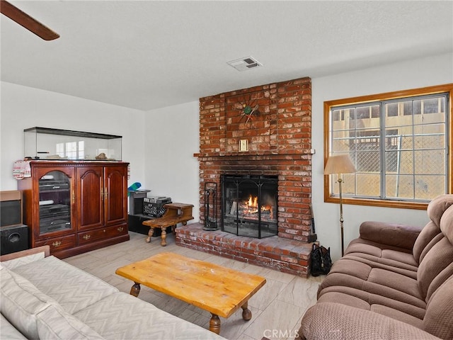 living room with a textured ceiling, a fireplace, and visible vents