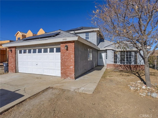 view of side of home with roof mounted solar panels, brick siding, and an attached garage