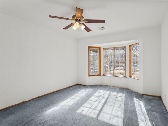 empty room featuring carpet floors, baseboards, visible vents, and a ceiling fan