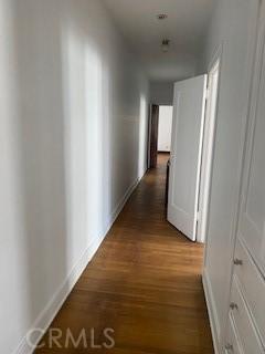 hallway with dark wood-style floors and baseboards