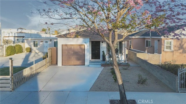 view of front of home with an attached garage, driveway, fence, and stucco siding