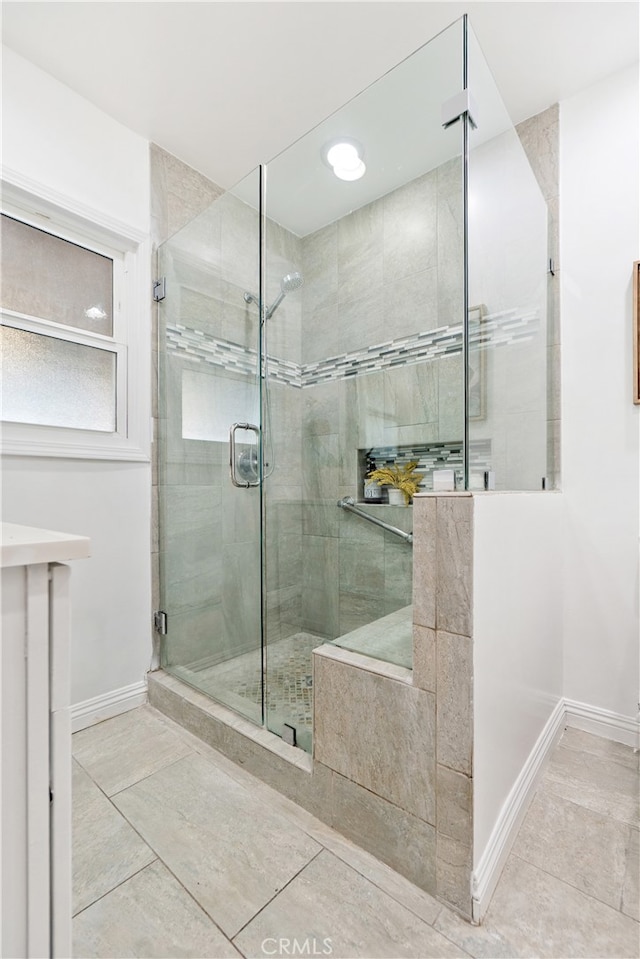 full bathroom with a stall shower, baseboards, and tile patterned floors