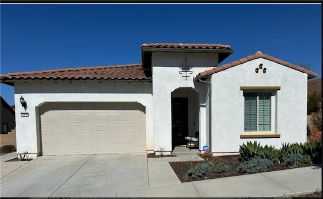 mediterranean / spanish-style home with concrete driveway, an attached garage, and stucco siding