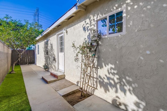 view of side of home featuring a patio area, fence, and stucco siding