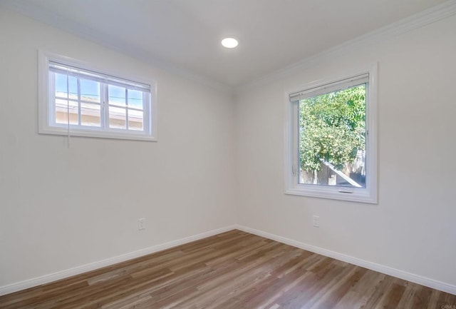 unfurnished room with crown molding, a healthy amount of sunlight, wood finished floors, and baseboards