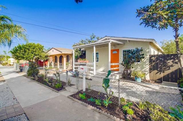 view of front facade with a fenced front yard, a gate, a porch, and stucco siding