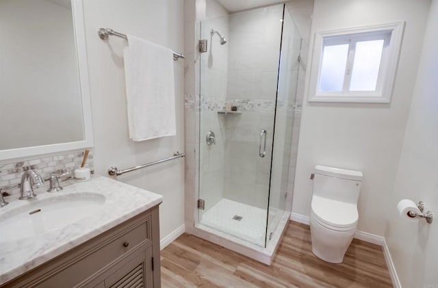 bathroom with decorative backsplash, toilet, wood finished floors, vanity, and a shower stall