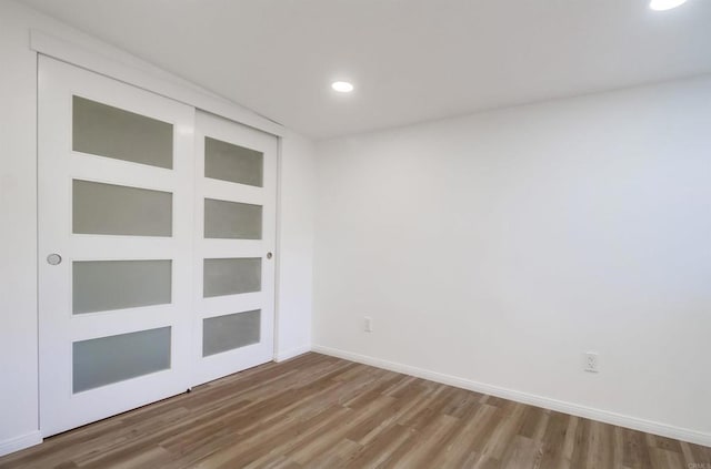 empty room featuring baseboards, wood finished floors, and recessed lighting