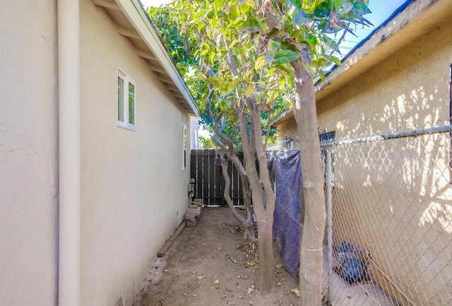 view of side of property with fence and stucco siding