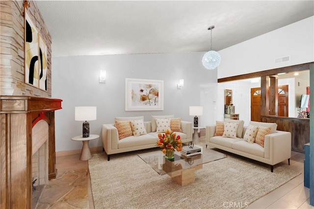 living area with baseboards, visible vents, and a large fireplace