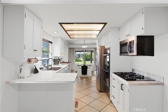 kitchen featuring a sink, white cabinets, light countertops, stainless steel microwave, and black gas stovetop