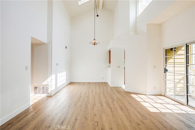 interior space featuring light wood finished floors, baseboards, visible vents, and beamed ceiling