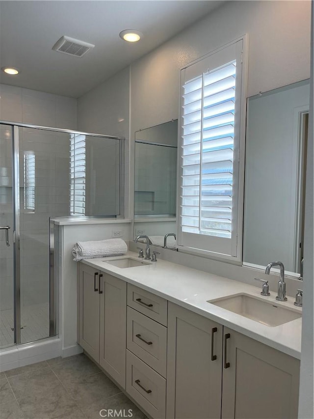 full bath featuring visible vents, a sink, a shower stall, and double vanity