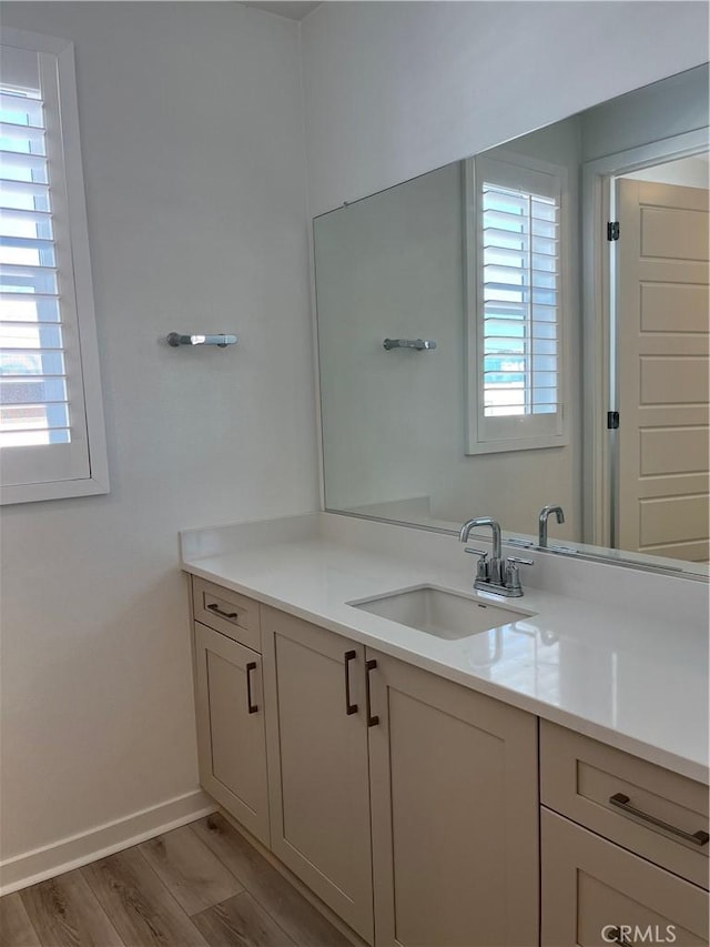 bathroom with a healthy amount of sunlight, baseboards, wood finished floors, and vanity