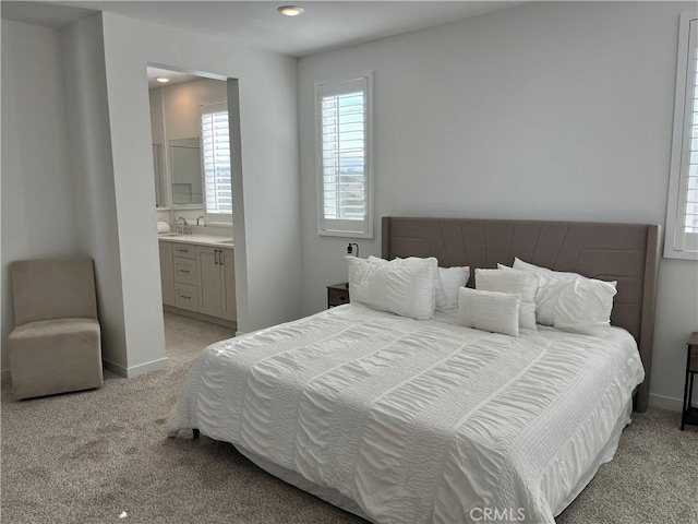 bedroom with recessed lighting, light colored carpet, a sink, ensuite bath, and baseboards