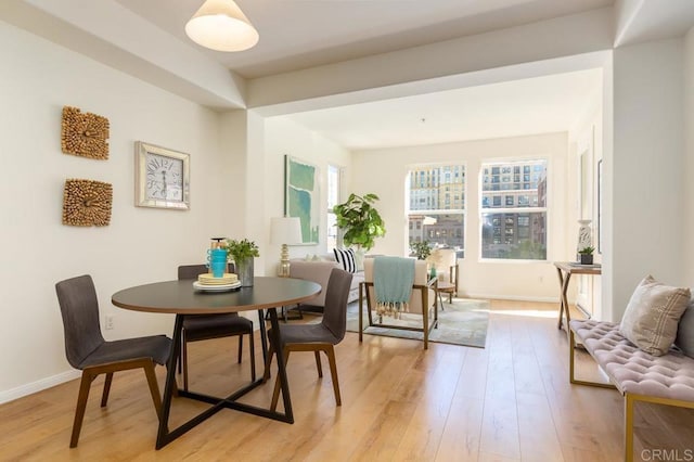 dining area with light wood-type flooring and baseboards