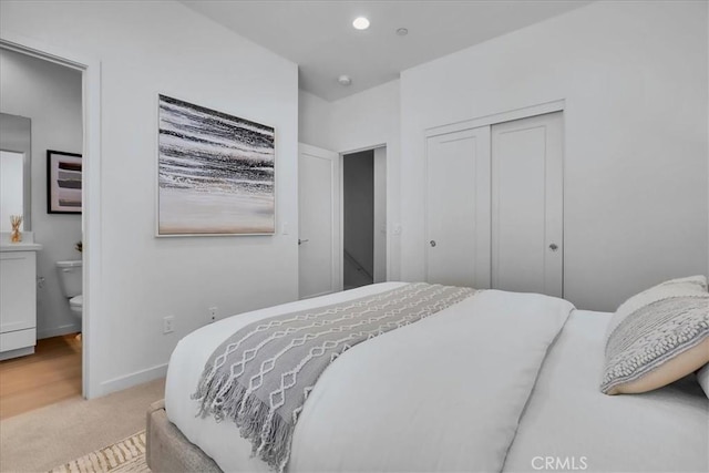 bedroom featuring recessed lighting, a closet, light colored carpet, connected bathroom, and baseboards