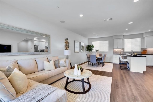 living room with baseboards, wood finished floors, visible vents, and recessed lighting