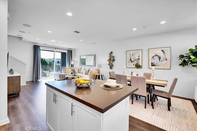 kitchen featuring dark wood-style flooring, white cabinetry, open floor plan, a center island, and dark countertops