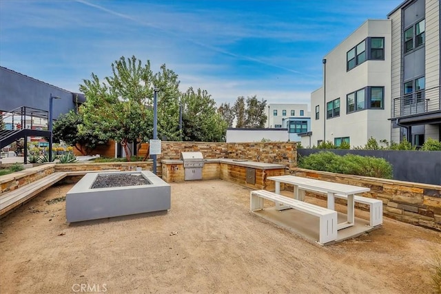 view of community with an outdoor fire pit, a patio area, and exterior kitchen