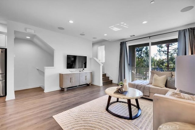 living room featuring light wood finished floors, stairs, visible vents, and recessed lighting