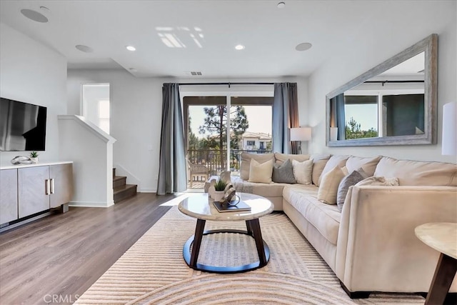 living area featuring recessed lighting, visible vents, wood finished floors, baseboards, and stairs