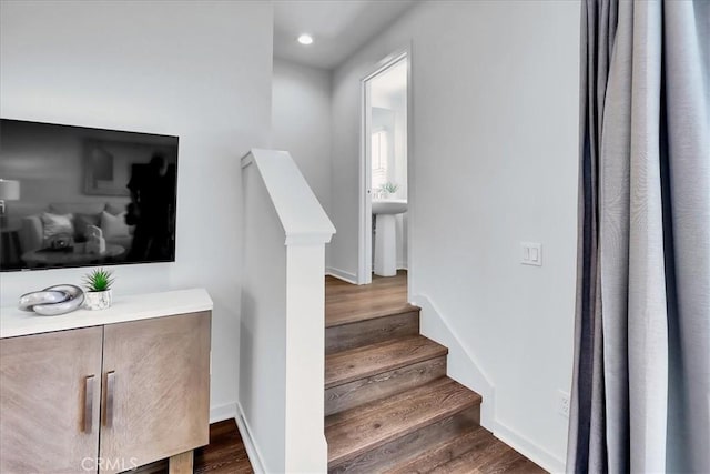 stairs with baseboards, wood finished floors, and recessed lighting