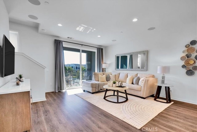 living area with wood finished floors, visible vents, and baseboards