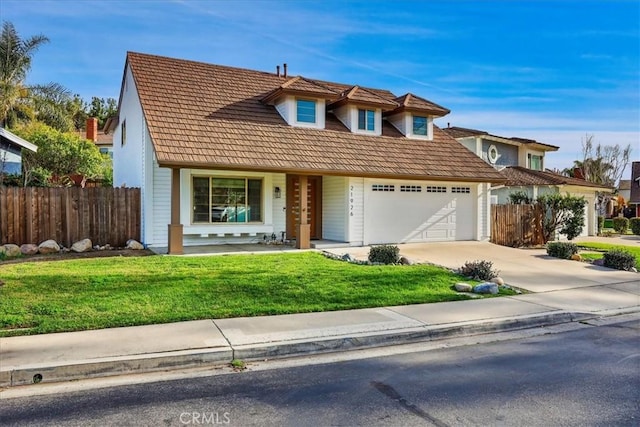 view of front facade with driveway, an attached garage, fence, and a front yard