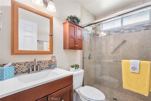 bathroom with toilet, tasteful backsplash, a stall shower, and vanity