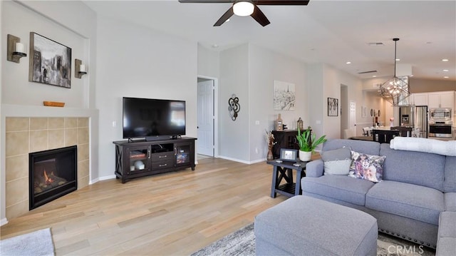 living room featuring light wood finished floors, baseboards, a ceiling fan, a fireplace, and recessed lighting