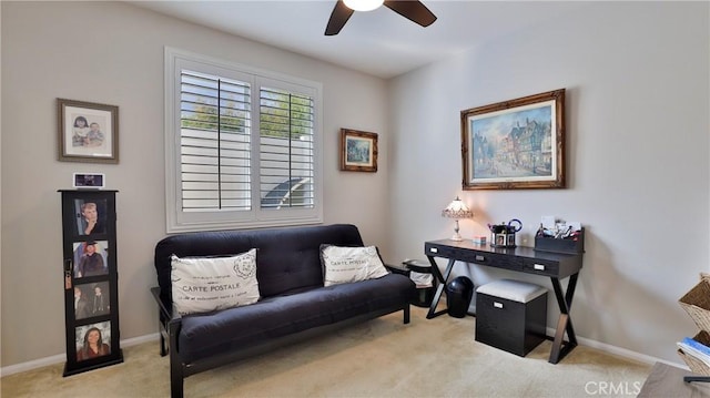 living area with a ceiling fan, light carpet, and baseboards