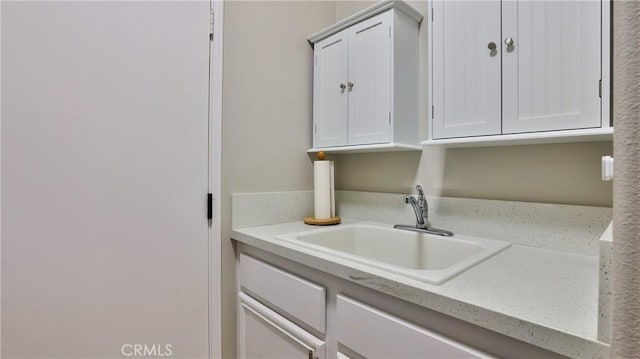 interior space featuring white cabinetry, light stone counters, and a sink