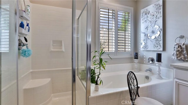 bathroom with a stall shower, a garden tub, and vanity