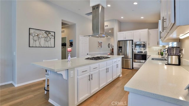 kitchen featuring a center island, light countertops, appliances with stainless steel finishes, white cabinets, and island range hood