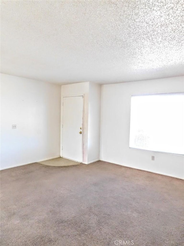 carpeted spare room featuring a textured ceiling